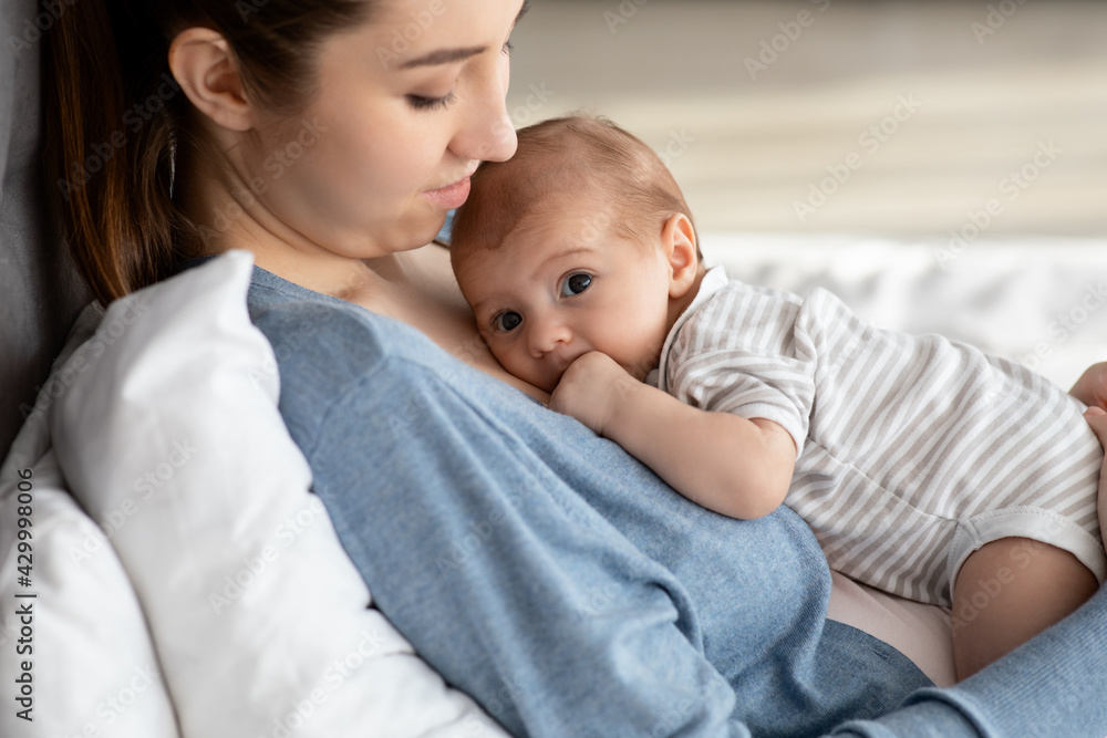 Portrait Of Adorable Little Newborn Baby In Bodysuit Resting On Mother's Chest Portrait Of Adorable Little Newborn Baby In Bodysuit Resting On Mother's Chest