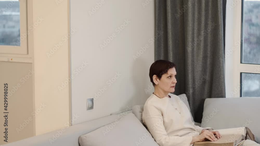 Mature woman read braille book on couch Mature woman read braille book on couch