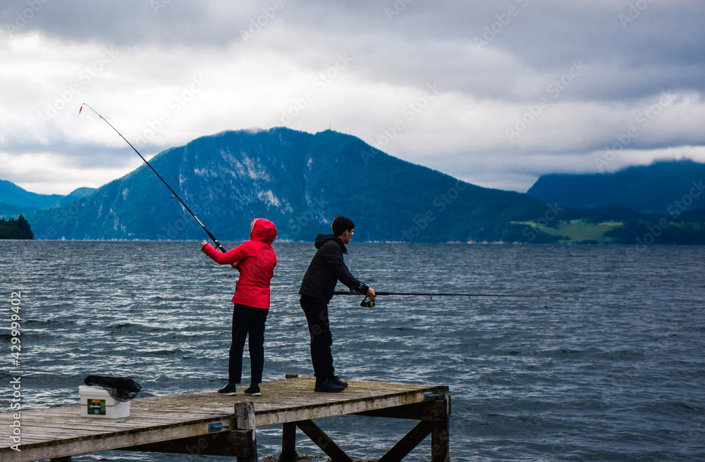 Guy and girl are fishing with fishing rods in Romsdal Fjord (Romsdalsfjord). Andalsnes. Norway. Guy and girl are fishing with fishing rods in Romsdal Fjord (Romsdalsfjord). Andalsnes. Norway.