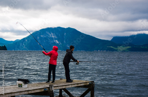 Guy and girl are fishing with fishing rods in Romsdal Fjord (Romsdalsfjord). Andalsnes. Norway.
