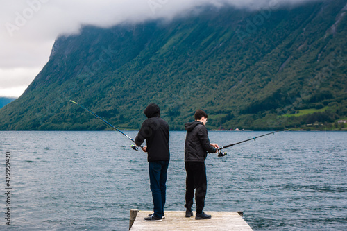 Guy and man are fishing with fishing rods in Romsdal Fjord (Romsdalsfjord). Andalsnes. Norway.