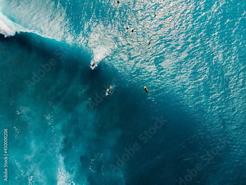 Aerial view of surfers in tropical blue ocean with waves at Bali. Top view