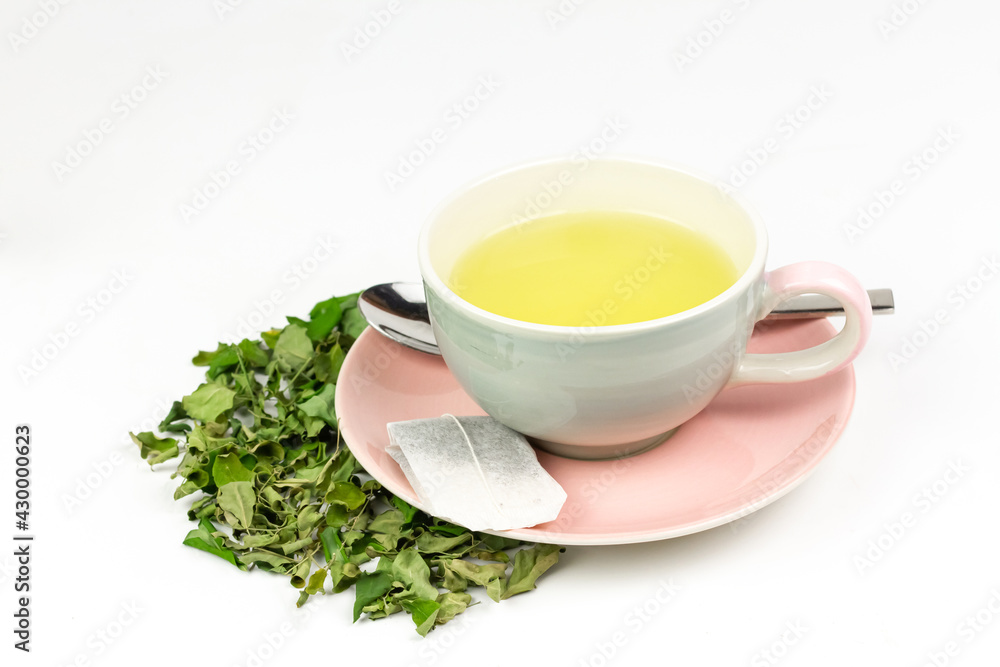 Moringa Tea in ceramic cup with dry green leaf isolated on white background. Moringa oleifera tropical herb healthy lifestyle concept. Moringa Tea in ceramic cup with dry green leaf isolated on white background. Moringa oleifera tropical herb healthy lifestyle concept.