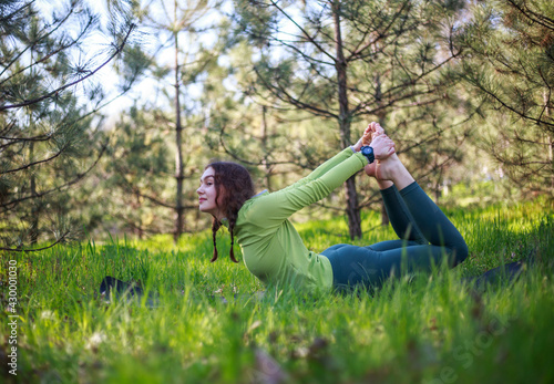 Girl doing yoga in fir park, fitness exercise outdoors, healthy lifestyle and freshness of pure nature © okostia