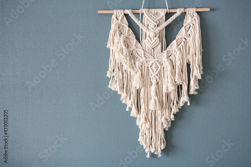 Macrame. Handmade macrame weaving and cotton threads on a rustic wooden stick. Scandinavian style in the interior, boho style. Cozy home photo