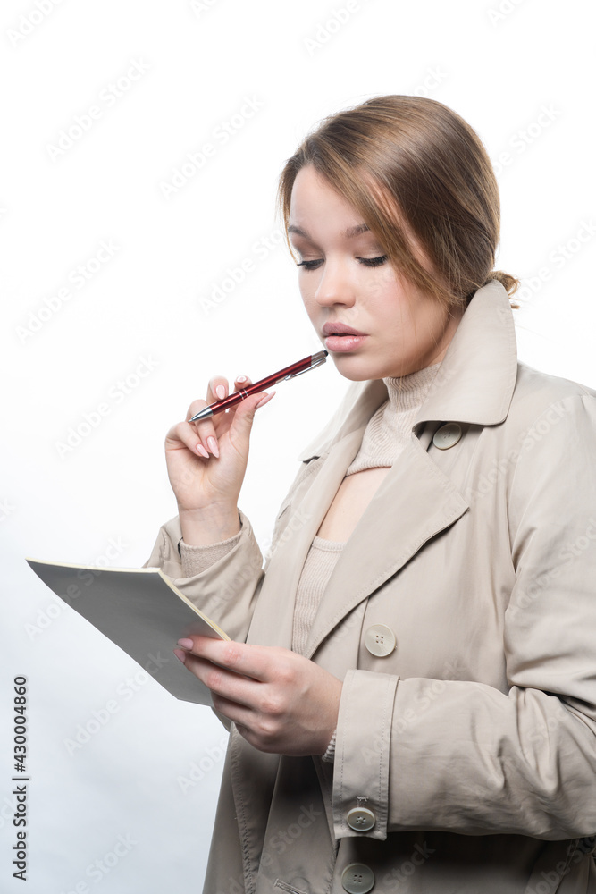 Portrait of a young girl, with long hair, holding a notebook and a pen in her hands Studio, white background Portrait of a young girl, with long hair, holding a notebook and a pen in her hands Studio, white background