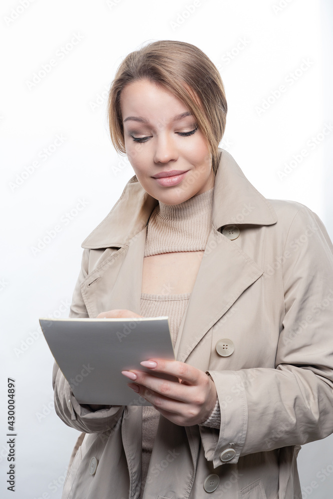 Portrait of a young girl, with long hair, holding a notebook and a pen in her hands Studio, white background Portrait of a young girl, with long hair, holding a notebook and a pen in her hands Studio, white background
