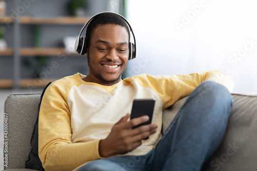 Joyful african american man watching videos on mobile phone