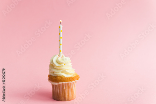 Birthday cupcake with candle on pink background
