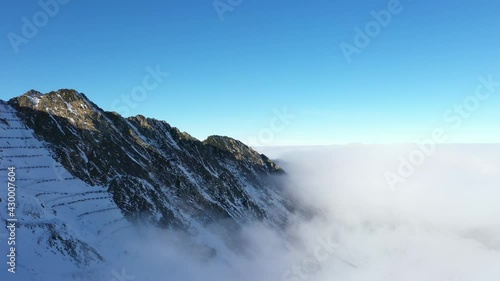 Flying over clouds and Fagaras mountains. Transfagarasan road in winter.