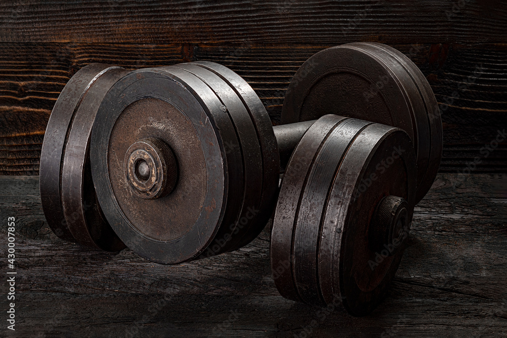 Fitness workout equipment. Dumbbell or barbell on a wooden floor surface Fitness workout equipment. Dumbbell or barbell on a wooden floor surface
