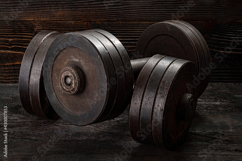 Fitness workout equipment. Dumbbell or barbell on a wooden floor surface