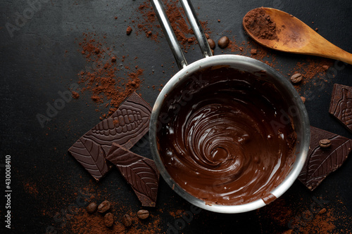 Melting chocolate in pot on dark photo