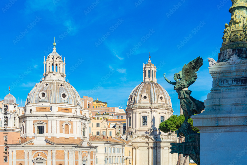 Venice square with views of the church of St. Mary of Loreto and the Most Holy Name of Mary in the Forum of Trajan in Rome, Italy on a sunny day with blue sky. Venice square with views of the church of St. Mary of Loreto and the Most Holy Name of Mary in the Forum of Trajan in Rome, Italy on a sunny day with blue sky.