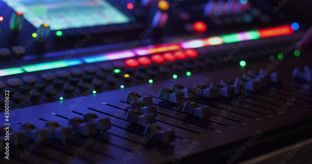 The sound engineer adjusts the sound at the concert using a large luminous sound console.