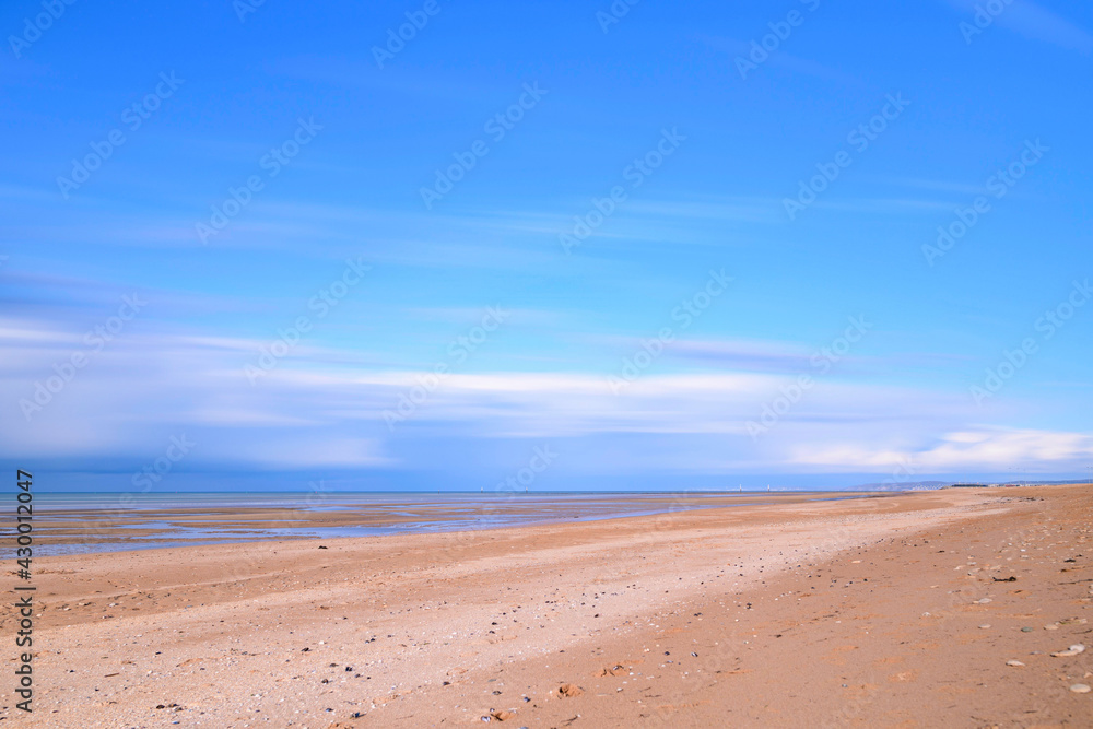 La plage de Sword beach à Ouistreham sous un ciel avec des nuages qui bougent en France, en Normandie, dans le Calvados, au bord de la Manche.