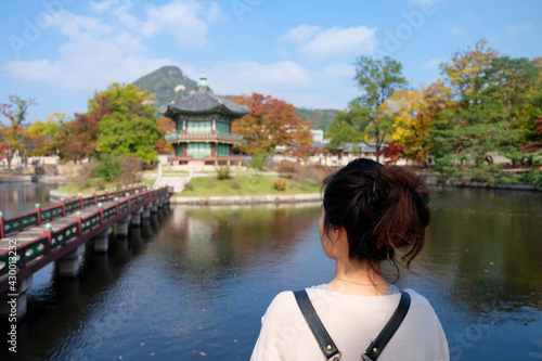 Focus young Asian tourist girl back during sightseeing around the beautiful on water pavilion background of Gyeongbokgung palace in autumn,South Korea. photo