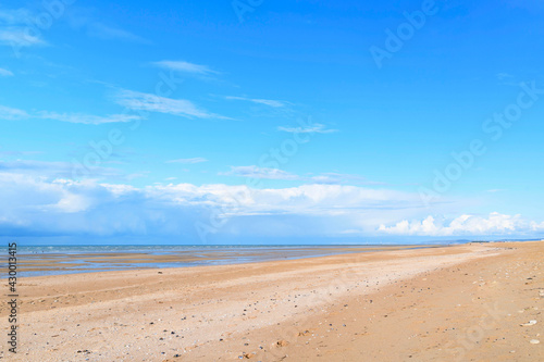La plage de Sword beach à Ouistreham sous un ciel avec des nuages en France, en Normandie, dans le Calvados, au bord de la Manche.