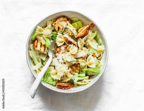 Caesar pasta salad in a bowl on a light background, top view. Delicious lunch, snack