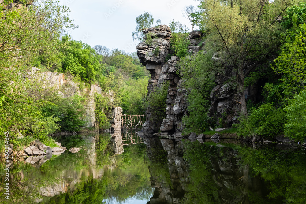 Calm river flowing in canyon with overhanging cliffs on two banks, Buky Canyon, Ukraine