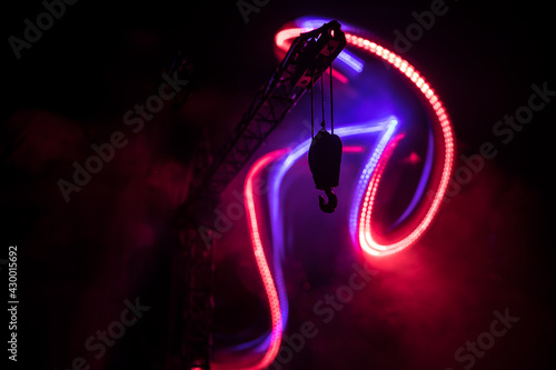 Abstract Industrial background with construction crane silhouette over amazing night sky with fog and backlight. Tower crane against the foggy sky at night.