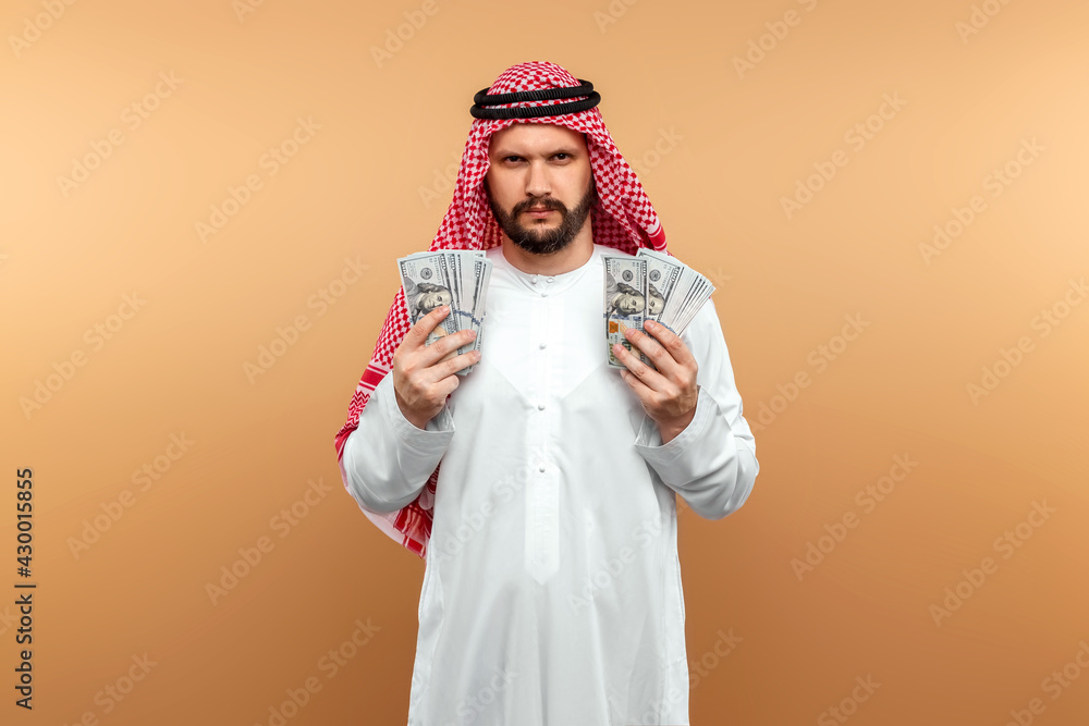 Arab man businessman in national clothes is holding dollars in his hands. Business concept in the middle east, oil sale, investment. Arab man businessman in national clothes is holding dollars in his hands. Business concept in the middle east, oil sale, investment.