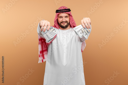 Arab man businessman in national clothes is holding dollars in his hands. Business concept in the middle east, oil sale, investment. photo