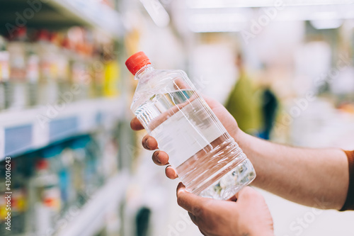 Foto A man in a hardware store holds a bottle of solvent.