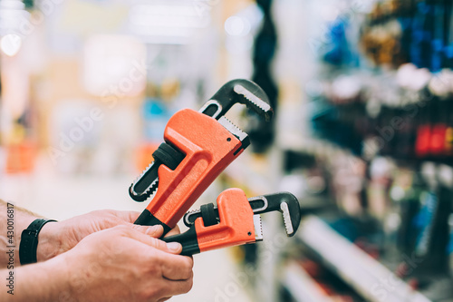 A man in a hardware store holds an adjustable wrench.
