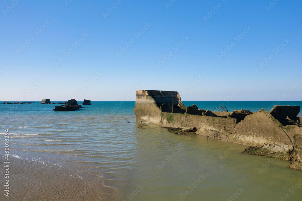Une partie des éléments flottant du port artificiel de Arromanches les bains au niveau de Asnelles sur la plage de sable en France, en Normandie, dans le Calvados, au bord de la Manche.