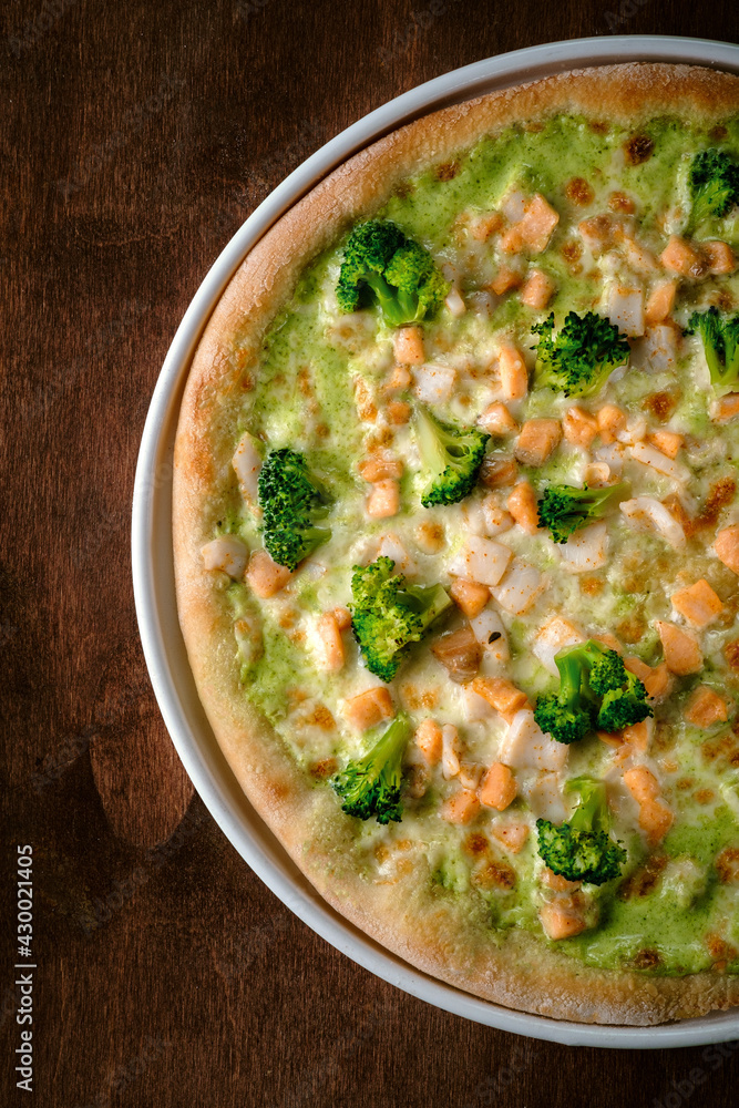 Half Pizza with broccoli, mozzarella and pesto sauce. Traditional Italian baked pizza on a wooden background