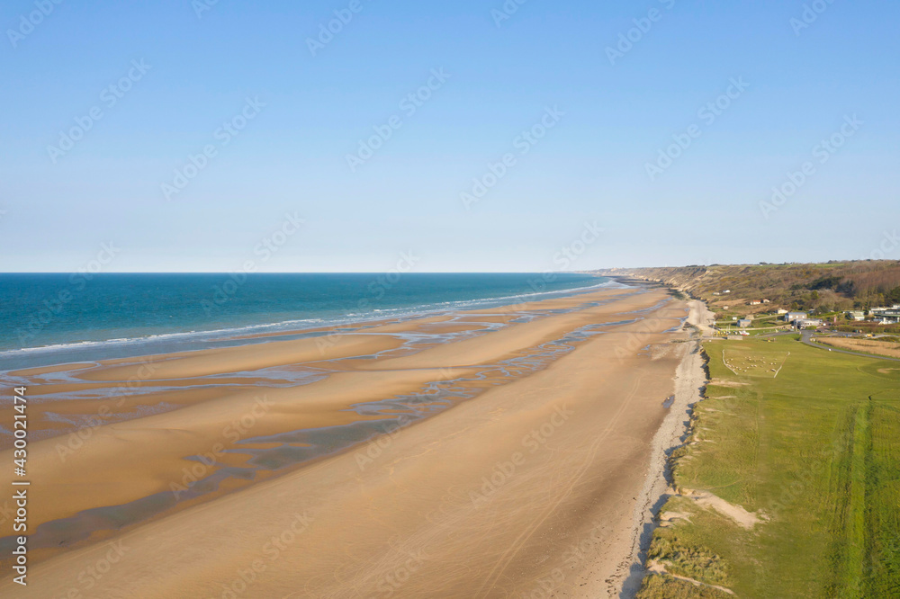 La plage et la butte de galets de Omaha beach en France, en Normandie, dans le Calvados, au bord de la Manche sous le Soleil.