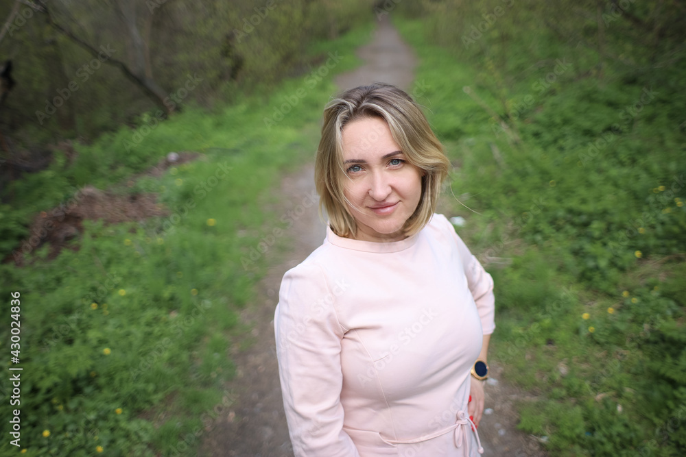 Beautiful girl stands in the park in the spring and looks at the camera Beautiful girl stands in the park in the spring and looks at the camera