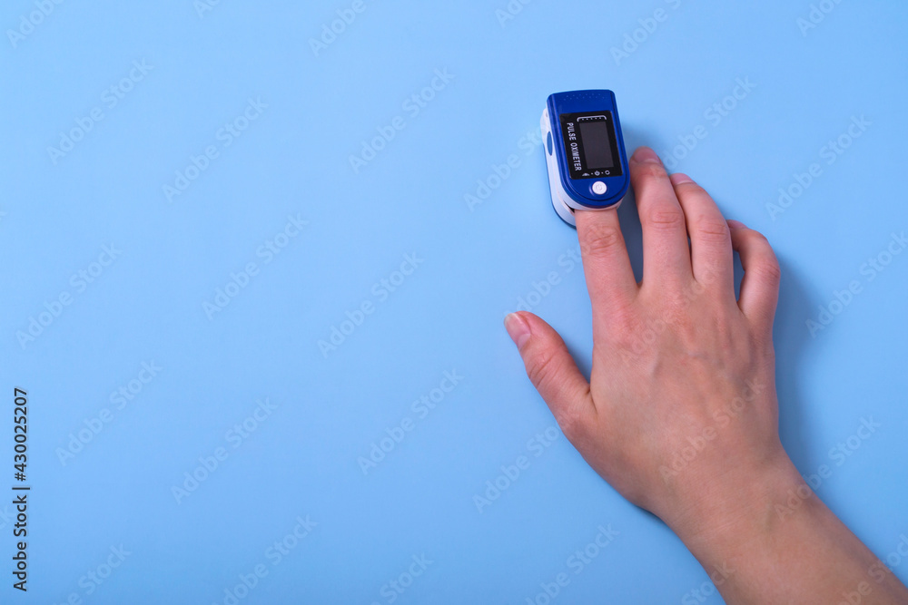 A pulse oximeter is on the woman's hand. A pulse oximeter used to measure heart rate and oxygen levels.. Covid-19 A pulse oximeter is on the woman's hand. A pulse oximeter used to measure heart rate and oxygen levels.. Covid-19