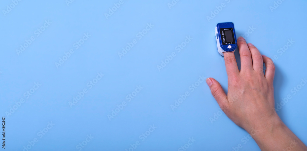 Banner.A pulse oximeter is on the woman's hand. A pulse oximeter used to measure heart rate and oxygen levels.. Covid-19 Banner.A pulse oximeter is on the woman's hand. A pulse oximeter used to measure heart rate and oxygen levels.. Covid-19