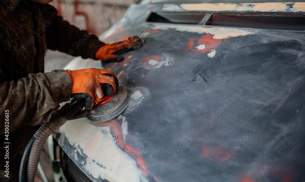 grinds a car putty, preparing a body for painting, car body repair. grinds a car putty, preparing a body for painting, car body repair.