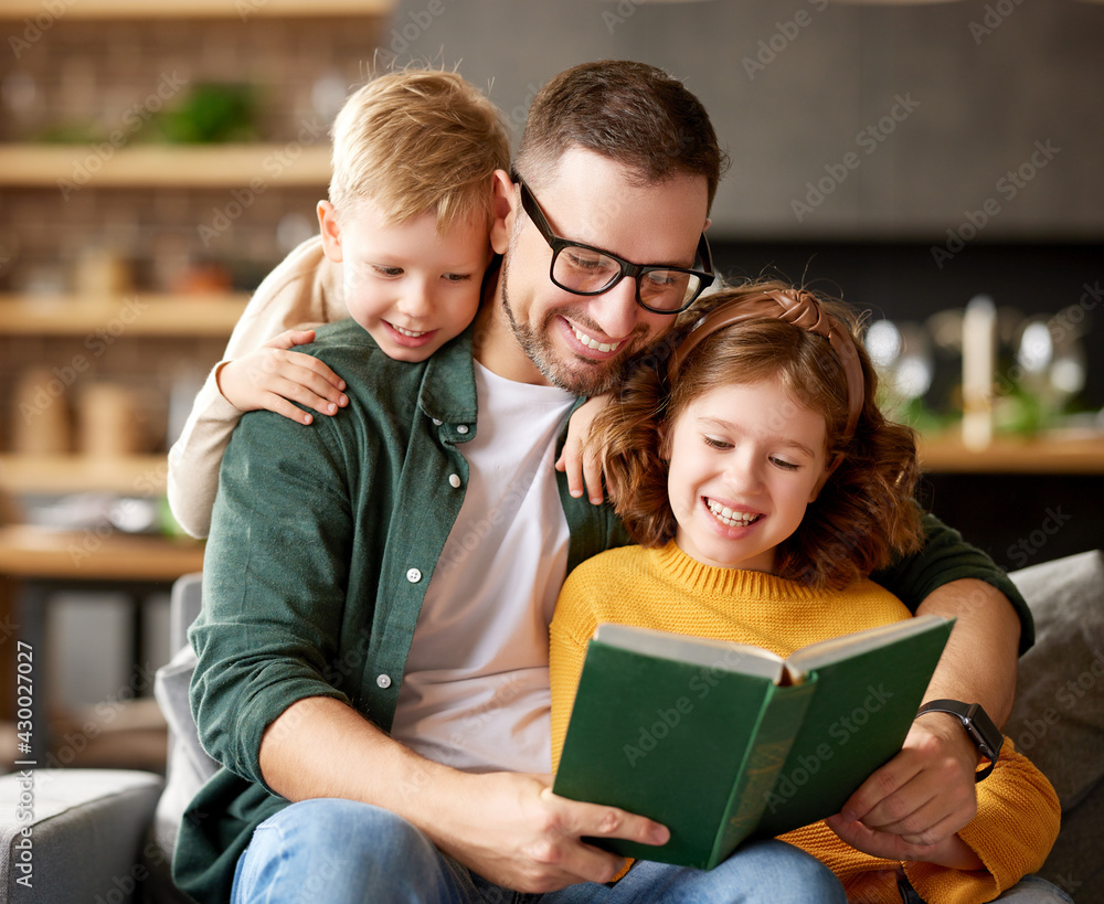 Young happy family with two kids reading book together while spending leisure time at home Young happy family with two kids reading book together while spending leisure time at home