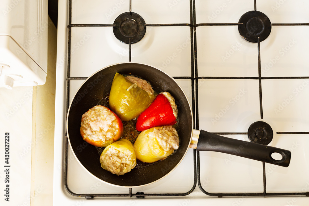 Steaming stuffed peppers in a skillet on a gas stove Stock Photo
