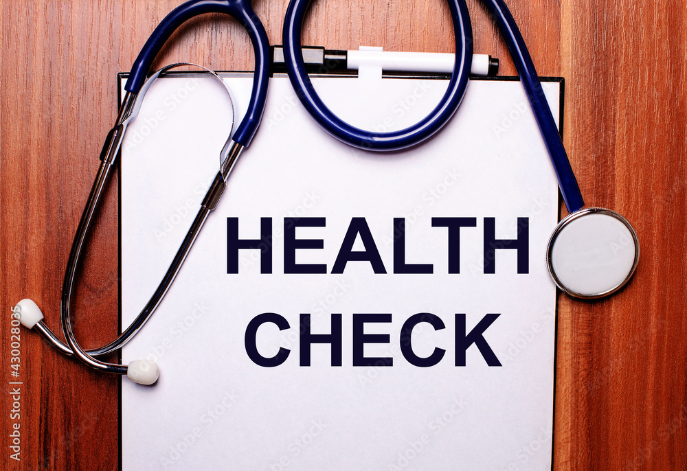 On a wooden background lies a stethoscope and a sheet of paper with the inscription HEALTH CHECK. Flat lay. Medical concept On a wooden background lies a stethoscope and a sheet of paper with the inscription HEALTH CHECK. Flat lay. Medical concept