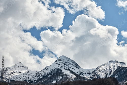 Snow-capped mountain peaks against a cloudy sky. Copy space. © ROMAN DZIUBALO