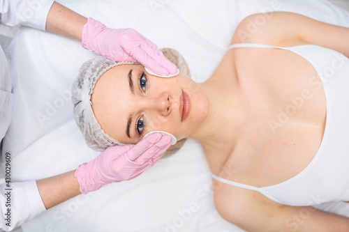 Beautiful happy woman receiving spa treatment. Cosmetologist in beauty salon cleaning woman's face with cosmetic sponges. Facial beauty. Perfect fresh clean skin. Youth and skin care concept 