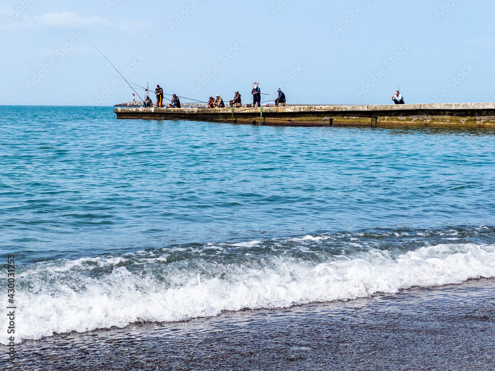 Sochi, Russia, April 13, 2021. People catch fish from the breakwater on the Black Sea coast Sochi, Russia, April 13, 2021. People catch fish from the breakwater on the Black Sea coast