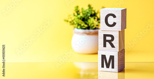 Photos Three wooden cubes with letters - crm - Customer Relationship Management, on blue table, space for text in left