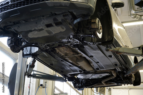 Modern car in a car service. Bottom view. The underside of the car, suspension and exhaust system elements. Car service and spare parts.