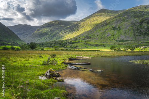 Sunken paddle boats in Lough Gummeenduff with warm sunlight on hills in beautiful Black Valley, MacGillycuddys Reeks mountains, Ring of Kerry, Ireland photo