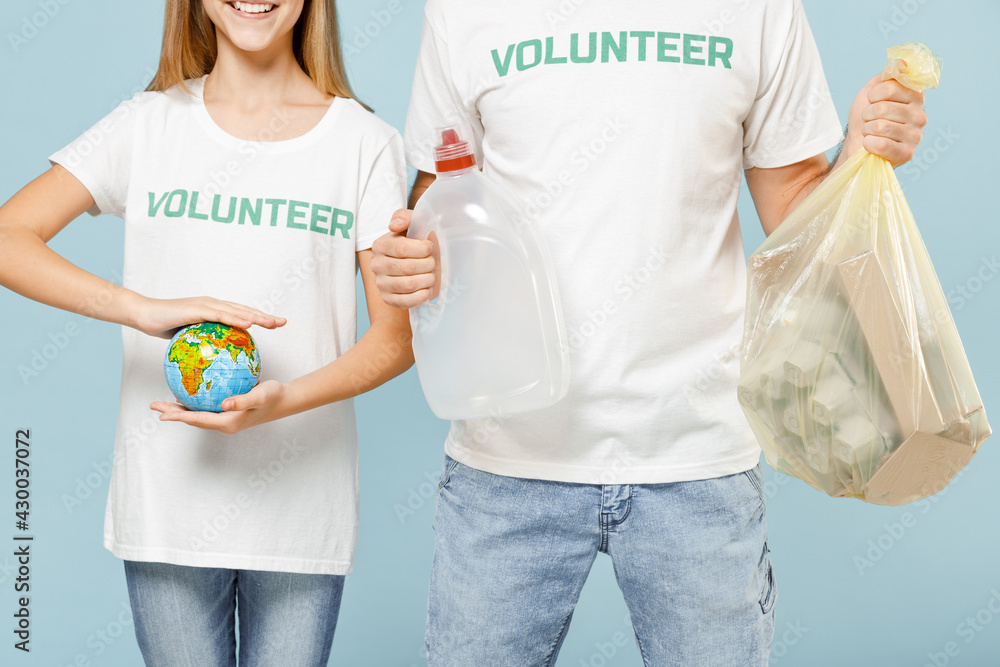 Closeup two couple teen girl man wears white t-shirt green title volunteer hold bag trash globe isolated on pastel blue color background Voluntary free team work assistance help charity grace concept Closeup two couple teen girl man wears white t-shirt green title volunteer hold bag trash globe isolated on pastel blue color background Voluntary free team work assistance help charity grace concept