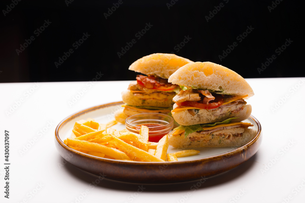 A plate with double sandwich with chicken meat and some fries.