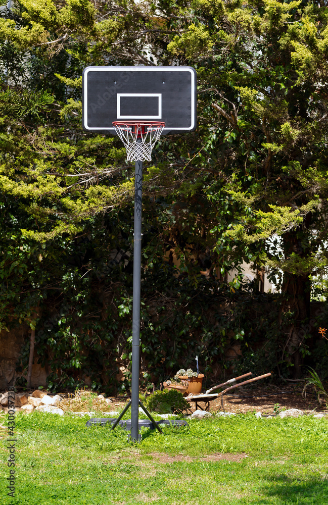 Outdoor Basketball ring costs in a garden on a grass against the background of green trees. Sports in the country. Photo of a backboard, Basketball hoop. Outdoor Basketball ring costs in a garden on a grass against the background of green trees. Sports in the country. Photo of a backboard, Basketball hoop.