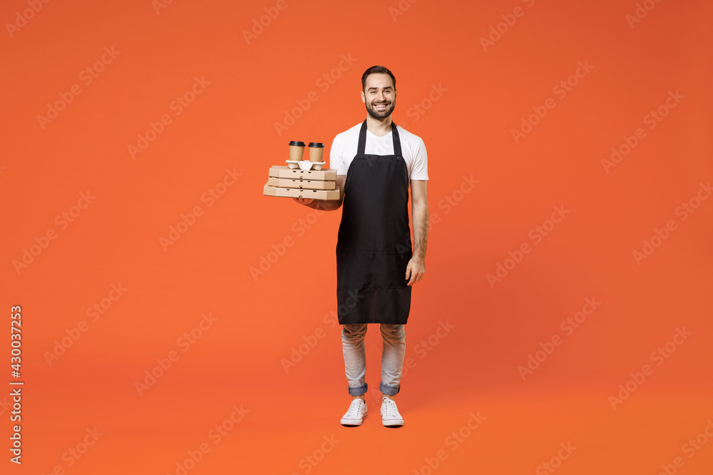 Full length young man barista bartender barman employee in black apron white t-shirt work coffee shop hold delivery cup pizza cardboard flatbox isolated on orange background Small business startup Full length young man barista bartender barman employee in black apron white t-shirt work coffee shop hold delivery cup pizza cardboard flatbox isolated on orange background Small business startup