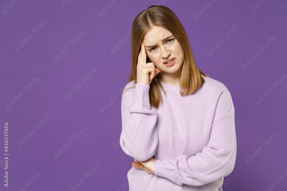 Young troubled puzzled thoughtful disappointed confused tired student woman in purple knitted sweater prop up forehead isolated on violet color background studio portrait People lifestyle concept. Young troubled puzzled thoughtful disappointed confused tired student woman in purple knitted sweater prop up forehead isolated on violet color background studio portrait People lifestyle concept.